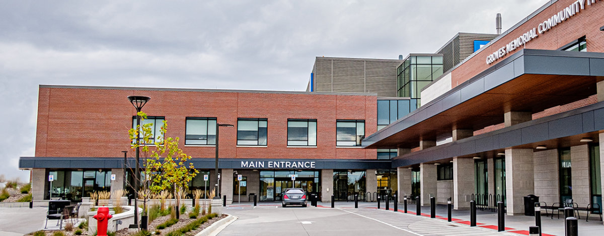 一座现代砖砌建筑的主入口，配有大型窗户和带顶棚的下客区。