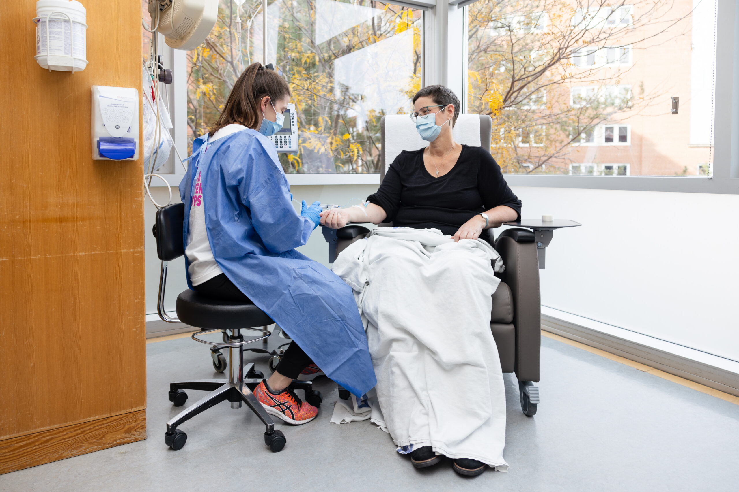 Nurse caring for a patient sitting in a chair in the systemic suite.